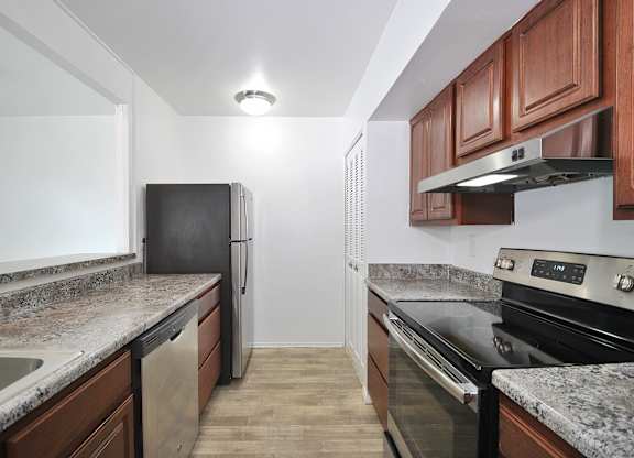 Renovated kitchen at Woodcrest Apartments in Westland, Michigan with stainless steel appliances, white cabinetry, and ample counter space.