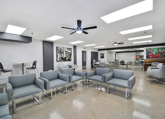 A room with grey couches and a ceiling fan.
