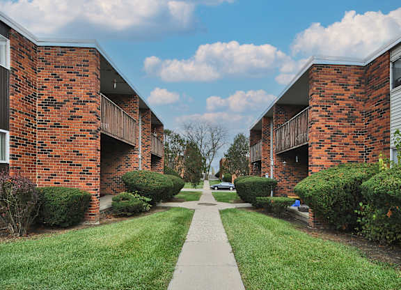 A long, narrow walkway separates two rows of red brick apartment buildings.
