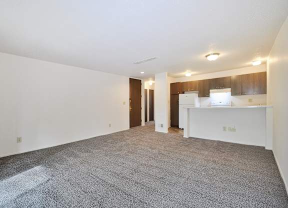 A spacious empty room with a carpeted floor and white walls.