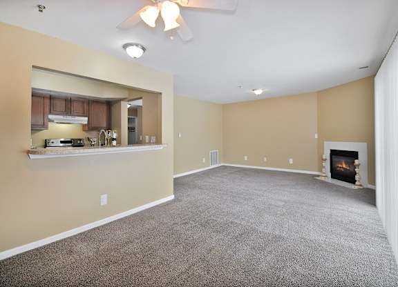 A spacious living room with a fireplace and a ceiling fan.