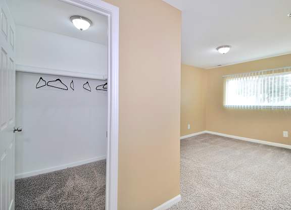 Comfortable bedroom at Woodcrest Apartments in Westland, MI featuring soft carpet flooring, a large closet, and large walk-in closets