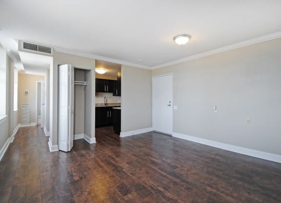 an empty living room with wood flooring and a kitchen