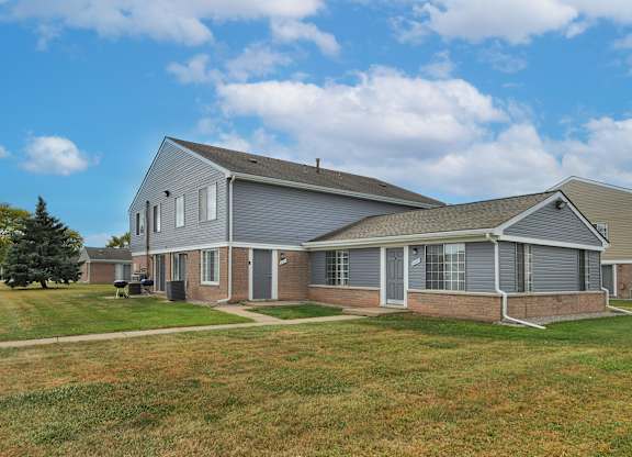 Exterior apartment building at Farmbrooke Manor Apartments in Clinton Township MI with well-kept landscaping and on-site parking