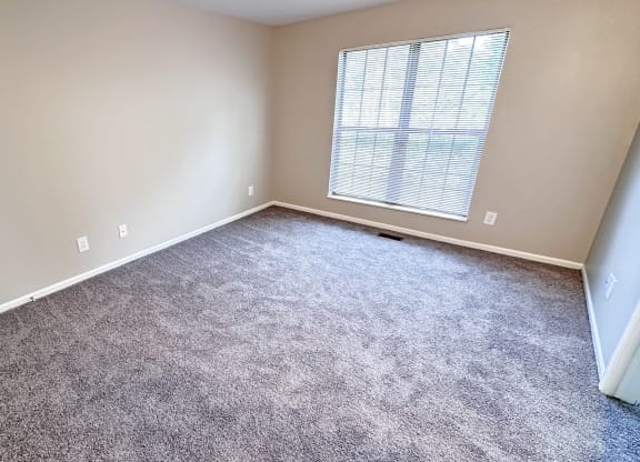 an empty room with carpet and a window