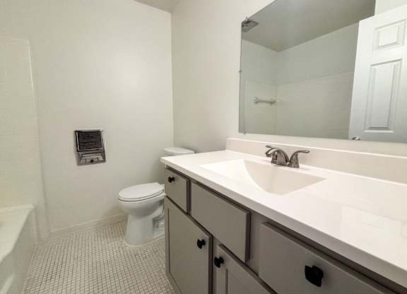A white bathroom with a toilet, sink, and mirror.