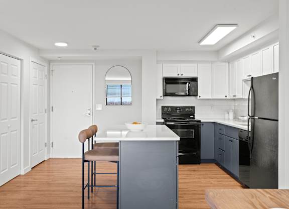 A kitchen with a black refrigerator and a bar stool.