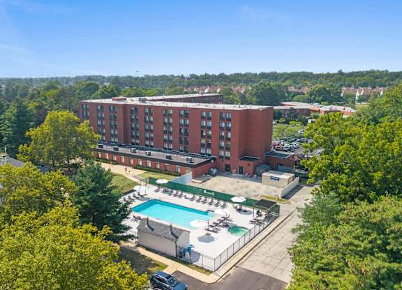 A large red brick building with a pool in front.