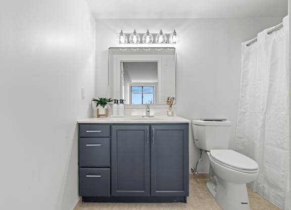 A bathroom with a white toilet and a mirror above a sink.