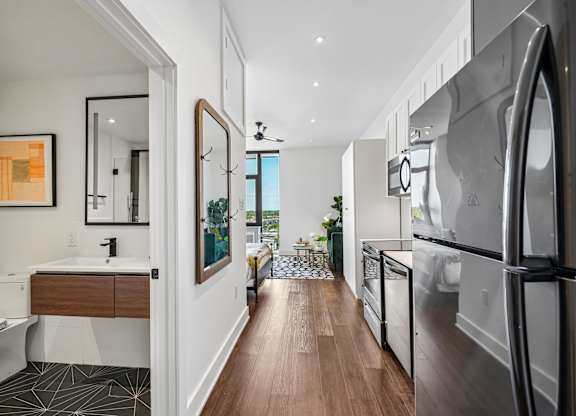 A modern kitchen with a refrigerator, sink, and wooden floors.