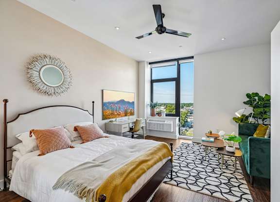 A bedroom with a large bed and a ceiling fan.