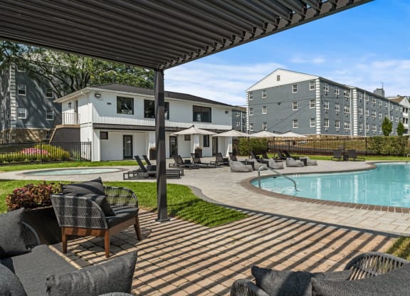a pool with lounge chairs and umbrellas at the enclave at woodbridge apartments in sugar  at Chestnut Hill Village, Philadelphia, Pennsylvania