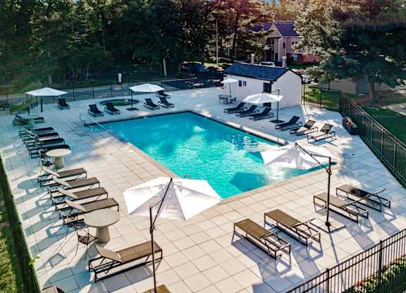 A large outdoor swimming pool surrounded by sun loungers and umbrellas.