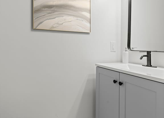A bathroom with a toilet, a sink, and a large painting on the wall.