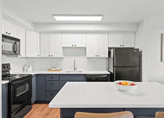 A modern kitchen with a bowl of fruit on the table.