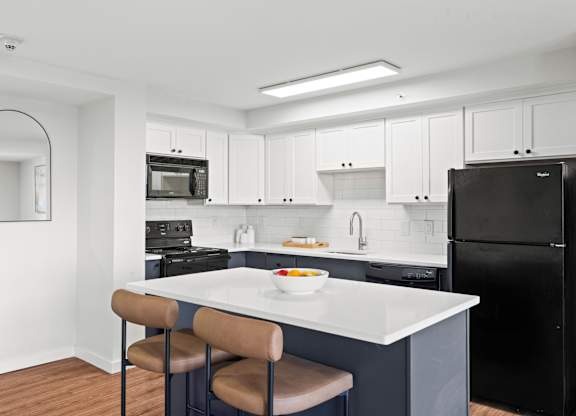 A kitchen with a white countertop and black appliances.