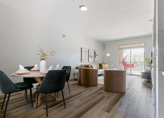 a living and dining area with a wooden floor and a sliding glass door leading to a balcony at Bristol Station Apartments, Carteret, New Jersey