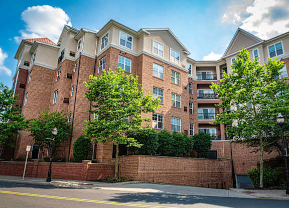 a red brick apartment building with trees in front of it at Park Square Apartments, Rahway, 07065