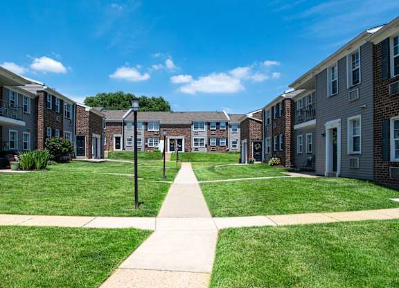 A sunny day at a residential area with apartment buildings and a walkway in the foreground.