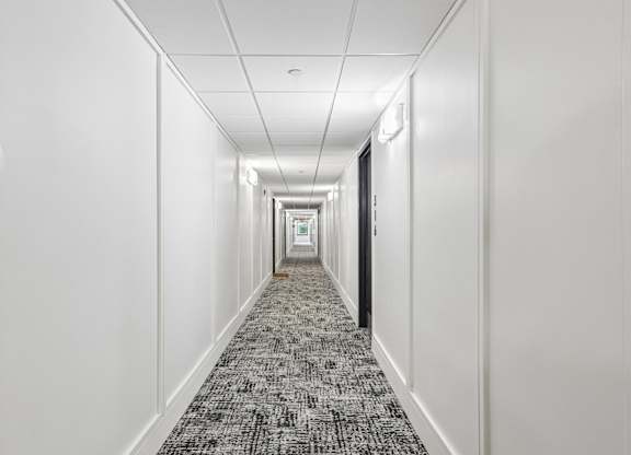 A long hallway with a carpeted floor and white walls.