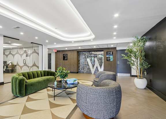 A modern waiting area with a green sofa, grey armchair, and a coffee table.