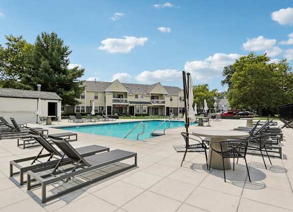 A pool with sun loungers and a table with chairs.