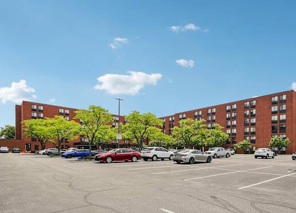 A parking lot with cars and a red building in the background.