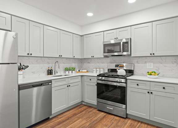 A kitchen with white cabinets and a stainless steel refrigerator.