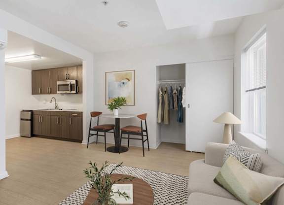 A well-lit, modern living room with a dining area and kitchen in the background.