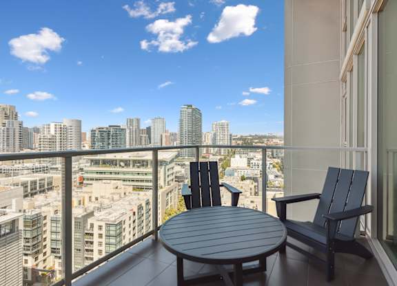 Balcony with a table and chairs and a view of the city at K1 Apartments, San Diego, CA