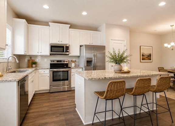 Spacious kitchen with an island, ample storage, stainless steel appliances and view into the living room.