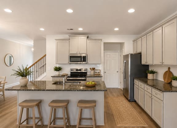 Spacious kitchen with an island, ample storage, stainless steel appliances and view into the living room.