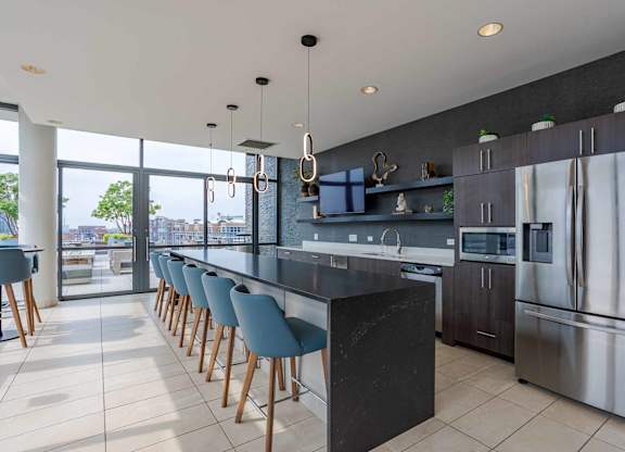 A modern kitchen with a long bar and stainless steel appliances.
