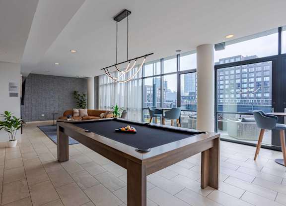 A pool table is in the middle of a room with a view of the city.