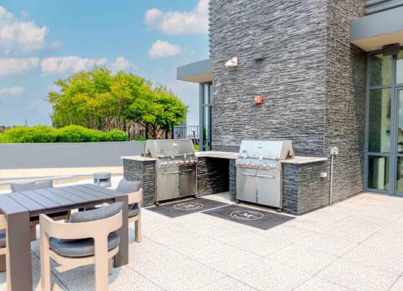 A patio with a table and chairs and a grill.