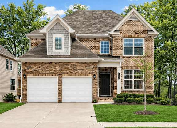A house with a brown brick facade and a white garage door.
