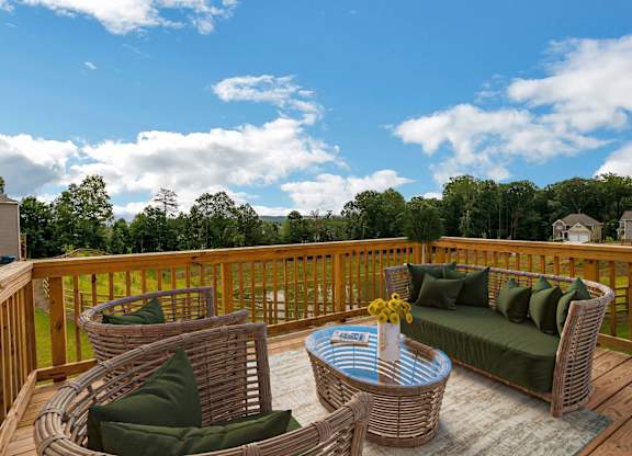 A wooden deck with a wicker sofa and table.