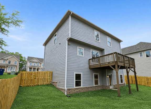 A grey house with a wooden fence in front.
