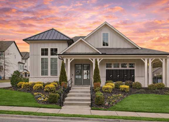 A house with a front yard and a black fence.