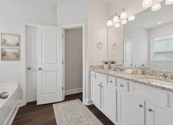 A bathroom with a white door, a white sink, and a white tub.