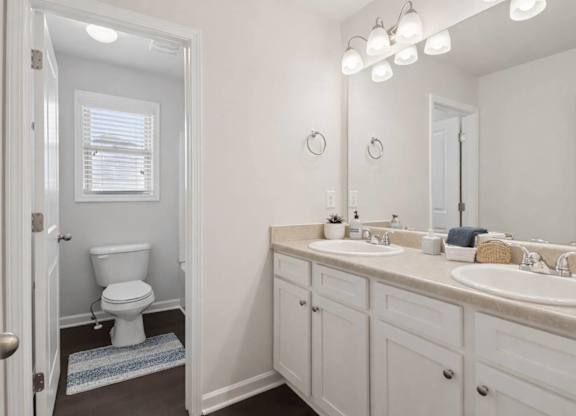 A white bathroom with a toilet, sink, and mirror.