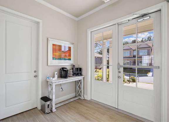 A white door is open to a room with a table and a painting on the wall.