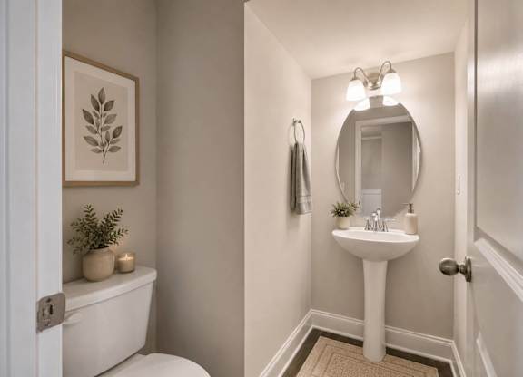 A bathroom with a toilet, sink, and mirror.