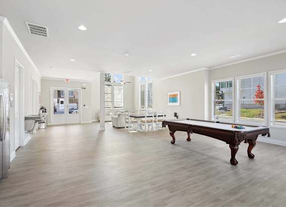 A spacious kitchen with a pool table and a refrigerator.