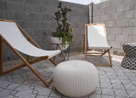 a patio with two chairs and a white ottoman and a mirror and plants at Novella Biltmore, Phoenix, AZ