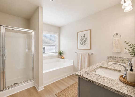 A bathroom with a marble countertop and a glass shower stall.