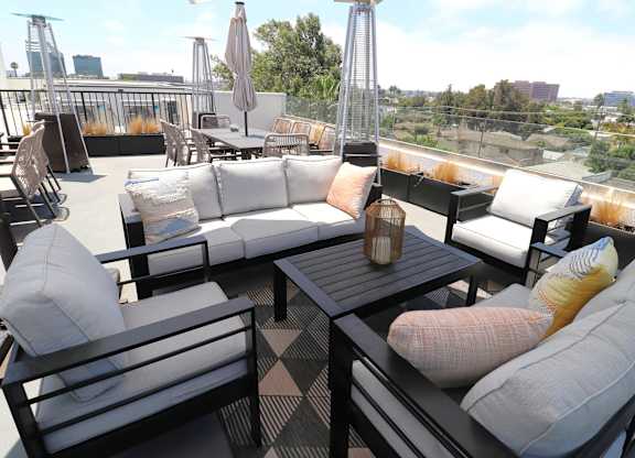 A patio with black furniture and a table with a vase on it.