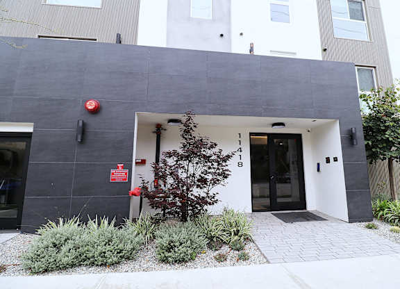 A modern building with a grey facade and a tree in front.