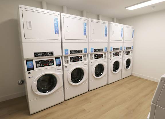 A row of white front loading washing machines in a laundromat.