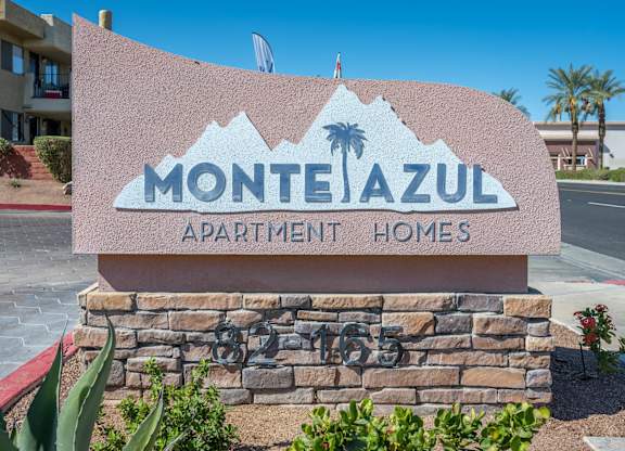 A sign for Montezul Apartment Homes with a mountain and palm tree graphic.